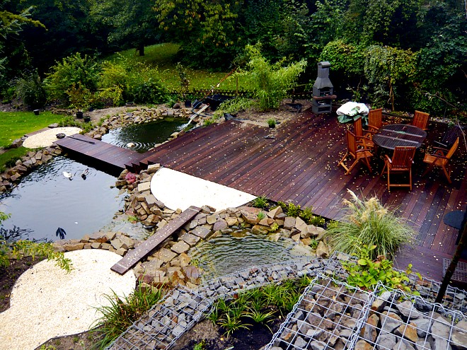 Gartenplanung mit Holzdeck am Teich, Gabionen mit Wasserfall